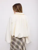 Campera Aurora de cuero sintético en color blanco, con cuello camisero, cierre frontal de cremallera, mangas amplias abullonadas y diseño corto.