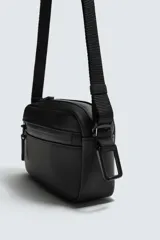 Bandolera negra con acabado engomado y textura. Cuenta con un compartimento principal con cierre de cremallera, un bolsillo plano interior y un asa de hombro ajustable y extraíble.