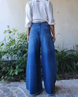 Pantalón de jean color beige, de corte recto y tiro alto, con ruedo deshilachado y cierre frontal con botón y cremallera.