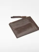 Monedero mediano de piel bovina de curtición vegetal, color rojo, con textura craquelada. Posee un compartimento principal con cierre de cremallera y un tarjetero en la parte trasera.