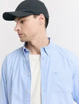 Camisa de corte clásico confeccionada en tejido oxford, con diseño de rayas verticales en tonos azul y blanco. Presenta cuello abotonado, cierre frontal con botones y bolsillo en el pecho con detalle de etiqueta bordada.