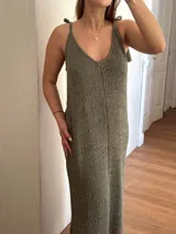 Vestido largo tejido en hilo de algodón y lurex color beige claro, con escote en V, tiras regulables en los hombros y tajos laterales. Presenta un patrón de puntos calados en forma de zigzag.