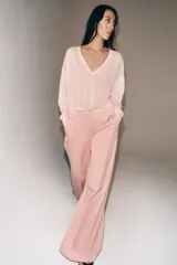 Pantalón de tiro medio con corte wide leg, confeccionado en algodón. Presenta cintura con trabillas, bolsillos laterales ocultos y detalle de pliegues en el delantero. Cierre frontal con cremallera, botón y ganchos metálicos.