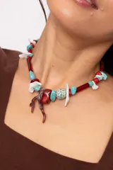 Collar corto elaborado con cuentas de turquesa reconstituida, piezas de nácar blanco, cuentas de cristal rojo y turquesa, y un dije central con forma de rama de coral.