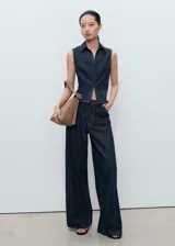 Top sin mangas estilo chaleco confeccionado en tejido de algodón y lino, con cuello solapa, cierre frontal con cremallera y costuras en contraste.