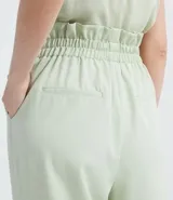 Pantalón color verde claro, de corte clochard, con cintura alta, pliegues frontales y bolsillos laterales.