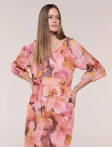 Vestido corto de gasa semitraslúcida con estampado floral en tonos rosados, naranjas y marrones. Posee escote en V, mangas tres cuartos acampanadas con abertura, y un fino lazo ajustable en la cintura. Incluye forro interior a tono.