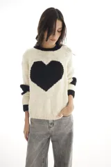 Sweater de lana merino color blanco marfil con un gran corazón negro en el frente, cuello redondo y mangas largas con puños acanalados negros.