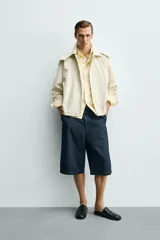 Parka cropped fit de tejido técnico ligero color beige, sin forro interior, con cuello solapa, capucha desmontable y manga larga. Cuenta con bolsillos de solapa en la cadera y cierre frontal con cremallera oculta por solapa con botones a presión.