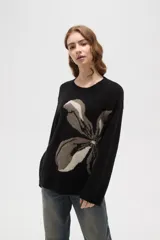 Sweater de punto jacquard con diseño floral abstracto en tonos tierra sobre fondo negro, de corte holgado, cuello redondo y manga larga.