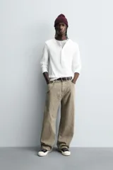 Pantalón de corte baggy fit confeccionado en tejido de algodón con textura y efecto lavado. Presenta diseño de cinco bolsillos, cierre frontal con cremallera y botón.