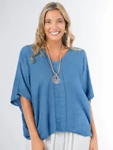 Remerón tipo poncho color azul, confeccionado en lino italiano, con escote en V, mangas amplias y diseño oversized.