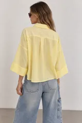 Camisa de lino blanca oversize, con cuello solapa, mangas anchas y cierre frontal con botones.