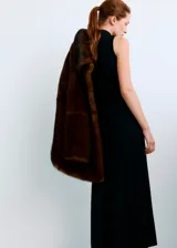 Vestido largo negro de punto con cuello alto, manga larga y detalle de aplique metálico dorado en la cintura.
