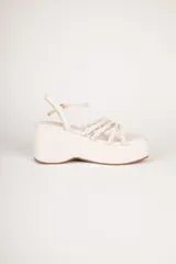 Sandalias negras con plataforma alta y taco corrido. Posee tiras delanteras trenzadas y tira ajustable al tobillo con hebilla metálica dorada.