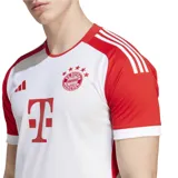 Camiseta de fútbol Adidas del FC Bayern Munich, modelo titular 23/24. Diseño blanco con mangas y detalles en rojo. Incluye logo de Adidas, escudo del club y sponsor T-Mobile en el frente.