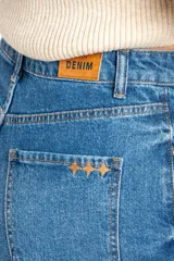 Short de denim azul de tiro medio y calce ajustado, con cinco bolsillos y cierre frontal con botón y cremallera.