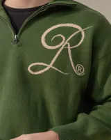 Sweater tejido de algodón en color verde oscuro, con cuello alto y cierre frontal parcial. Presenta un diseño de letra R bordada en color beige en el frente.