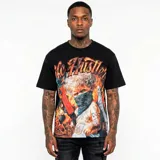 Camiseta negra de corte oversize con estampado gráfico frontal que presenta a un bebé con alas, pañuelo en el rostro y arma, rodeado de llamas, junto a la inscripción 'Life Hustler'.