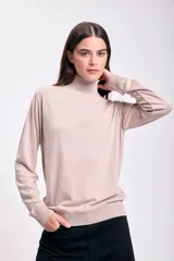Polera beige de cuello alto y mangas largas.