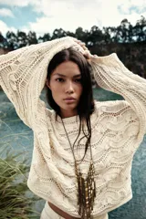 Sweater color crudo de punto calado con cuello barco y manga larga acampanada.