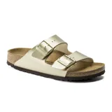Sandalia Birkenstock modelo Arizona con dos correas ajustables con hebillas metálicas. Presenta una plantilla anatómica de corcho y látex con suela de goma, en color dorado.