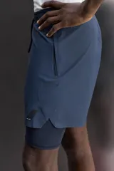 Short de entrenamiento deportivo con diseño 2 en 1, que incluye una capa exterior de tejido técnico ligero y una malla interior ajustada. Cuenta con cintura elástica con cordón de ajuste, bolsillos laterales con cierre y aberturas en el bajo.