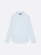 Camisa celeste de corte slim confeccionada en popelín de algodón con Flex Technology, cuello inglés, puños redondeados con botones y logo de Tommy Hilfiger bordado en el pecho.