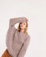 Buzo tejido a mano con lana, color rosa con motas de colores. Diseño oversized, largo entre la cintura y la cadera, con detalle de trenzas en las mangas.