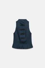 Top peplum sin mangas en color azul denim, con cuello mao y cierre frontal con alamares decorativos negros. Cuenta con un bajo acampanado con pliegues y cierre lateral con cremallera oculta.