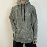 Canguro con capucha de corte oversize en color gris con efecto lavado ácido. Presenta un pequeño estampado gráfico en el pecho y una etiqueta distintiva en el puño. Incluye bolsillo frontal tipo canguro y cordones ajustables en color negro.