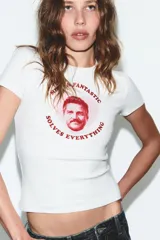 Camiseta blanca de manga corta y cuello redondo, con estampado frontal de Pedro Pascal en un círculo rosado y texto que dice "Mister Fantastic Solves Everything".