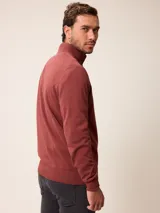 Sweater de punto color gris, con cuello alto y cierre frontal parcial con detalle de tela a cuadros en el interior. Presenta puños y ruedo acanalados y logo bordado en el pecho.