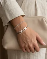 Pulsera de acero quirúrgico con dos dijes de símbolos de infinito en cerámica blanca y cadena doble eslabonada.