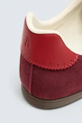 Zapatilla de cordones de estilo retro, con parte superior de serraje color bordó y detalles en piel lisa color rojo. Suela ultrafina de goma en tono marrón oscuro.