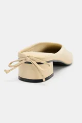 Bailarina destalonada en piel color beige, con tacón en bloque, acabado en punta redonda y detalle de lazo en la parte trasera.