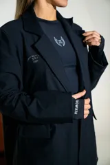 Blazer de lycra color negro, de corte oversize y diseño estructurado con solapas clásicas. Presenta detalles bordados sutiles en la solapa y en el puño de la manga.