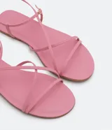 Sandalia plana de mujer color amarillo mostaza, con tiras finas que cruzan sobre el empeine y una tira con hebilla ajustable alrededor del tobillo.