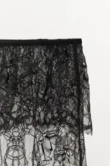 Short de encaje negro semitransparente, de tiro medio, con cintura elástica ajustable con lazada, detalle de volantes y bajo con acabado en ondas.