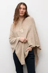 Capa tejida de corte asimétrico en tono beige, con escote redondo y diseño holgado.