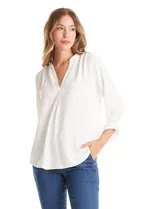 Blusa de color blanco con escote en V y cuello mao. Presenta mangas largas con presilla y botón para regular el largo, y un corte holgado con ruedo redondeado.