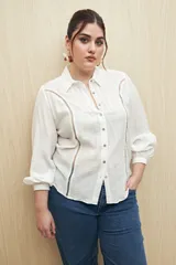 Camisa blanca de manga larga con cuello clásico y botones de nácar. Presenta detalles calados en el frente.