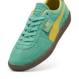 Championes Puma Palermo confeccionados en gamuza de color verde turquesa con detalles en amarillo, incluyendo la franja lateral caracteristica y el interior. Cuenta con suela de goma marrón y la etiqueta con el nombre del modelo y el logotipo de Puma en color dorado sobre el lateral externo.