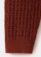 Sweater marrón de punto con volantes en los hombros, cuello redondo y mangas largas.