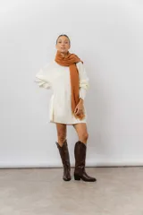 Buzo tipo sweater de punto color blanco, con diseño de trenzas verticales, cuello redondo, mangas largas y tajos laterales. Presenta un corte oversize y largo extendido.