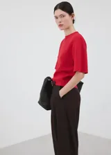 Chaleco rojo de punto fino, de diseño recto, cuello redondo y manga corta.