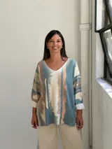 Sweater de punto con diseño abstracto de rayas verticales en tonos petróleo, beige y terracota. Presenta escote en V, corte holgado y mangas largas con puños vueltos.