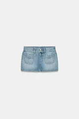 Falda mini de denim en tono azul claro, con tiro medio, trabillas para cinturón y bolsillos de plastrón en el frente. Presenta cierre frontal con cremallera y botones metálicos.