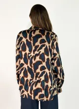 Camisa de manga larga con cuello camisero y cierre frontal de botones, confeccionada en tela fluida con estampado animal print en tonos marrones y negros.
