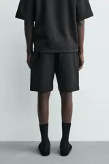 Bermuda estilo jogger de ajuste relajado, color negro, confeccionada en tejido interlock de algodón. Cuenta con cintura elástica ajustable mediante cordón, bolsillos delanteros tipo vivo y diseño liso.